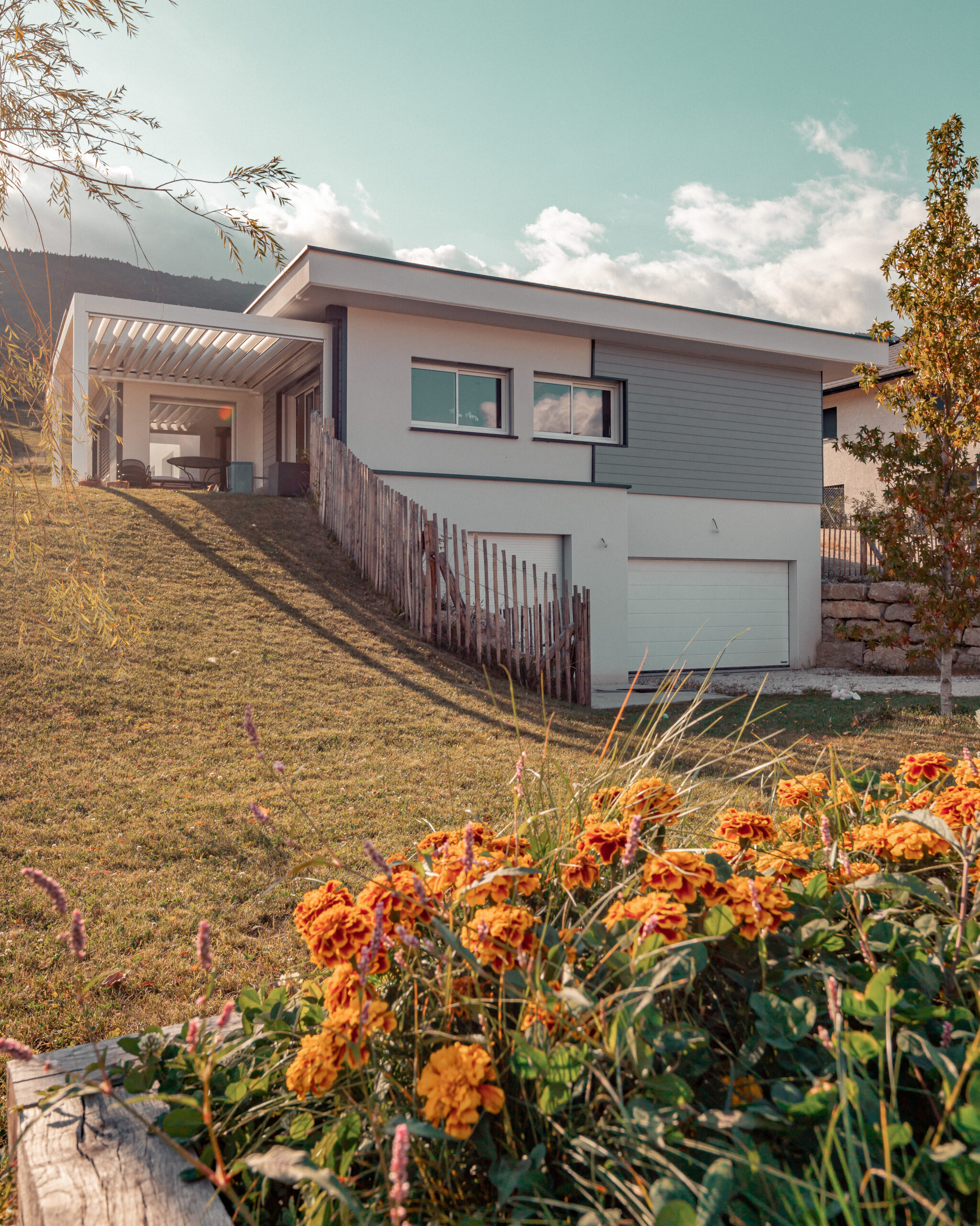 Coucher de soleil sur cette maison contemporaine construite sur un terrain en pente par Maisons Alpes Savoie à la Motte Servolex, en Savoie.